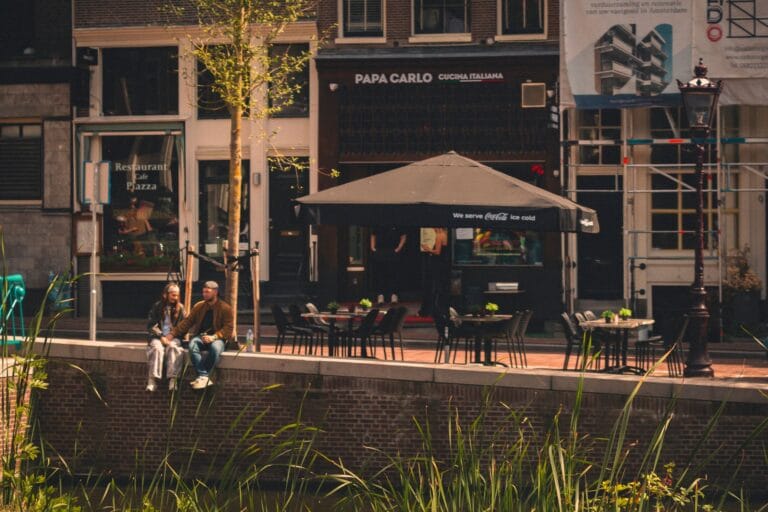 Kawiarnia nad kanałem w Amsterdamie z ogródkiem i szyld